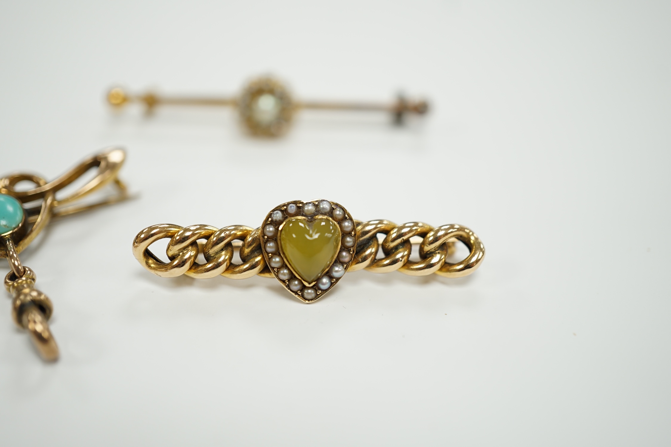 An Edwardian Art Nouveau 9ct gold and turquoise set brooch, width 38mm, a yellow metal (stamped 20) and seed pearl cluster set bar brooch and one other yellow metal and gem set brooch.